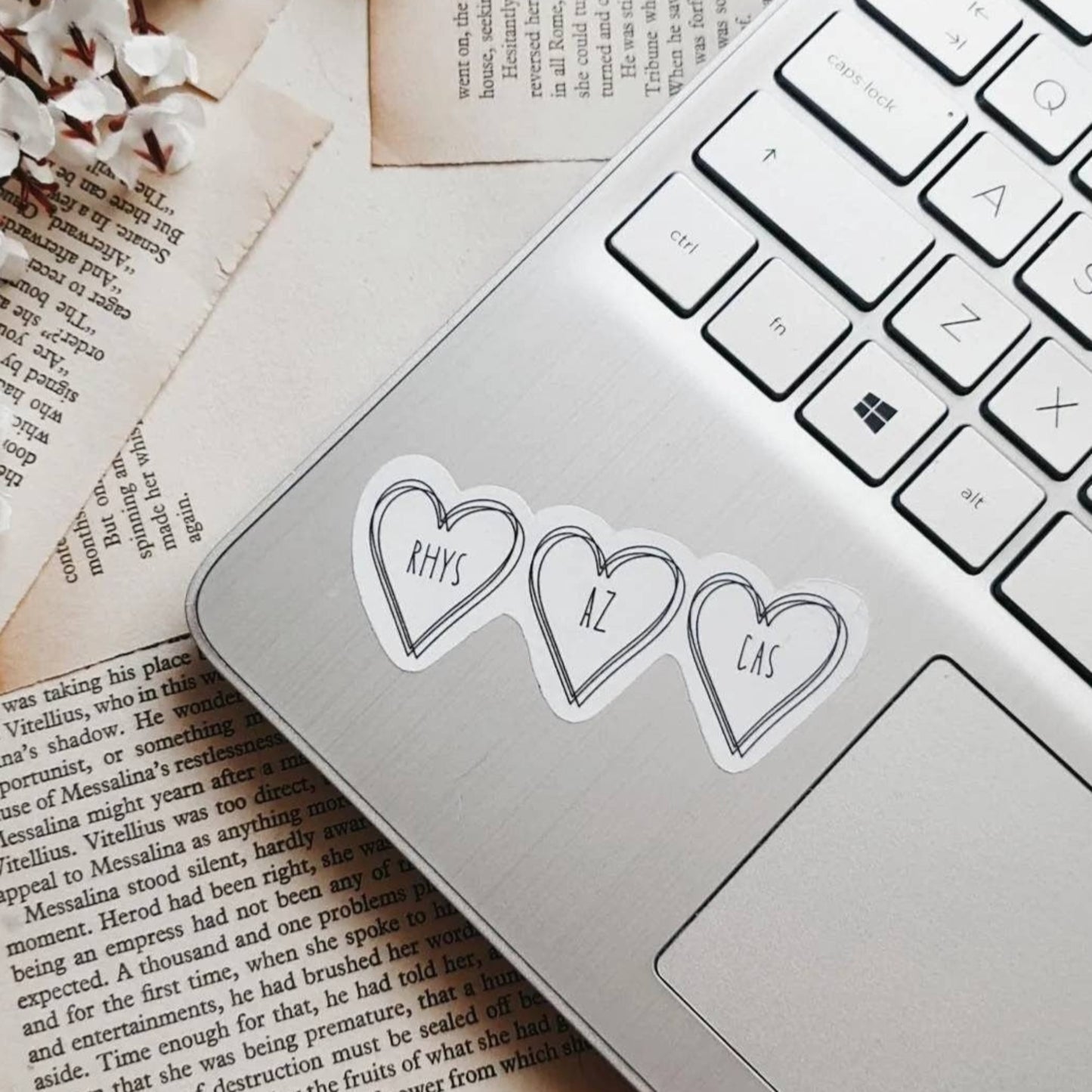 white sticker with three black heart outlines. The sticker is on a laptop.